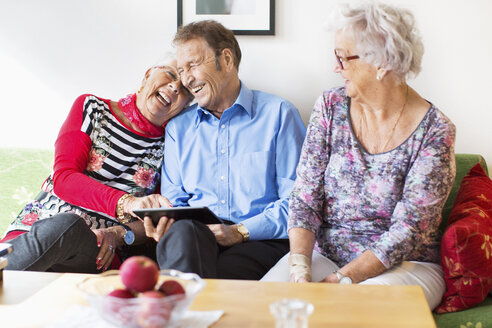 Glückliches Seniorenpaar, das ein digitales Tablet von einer Freundin im Pflegeheim benutzt - MASF04950