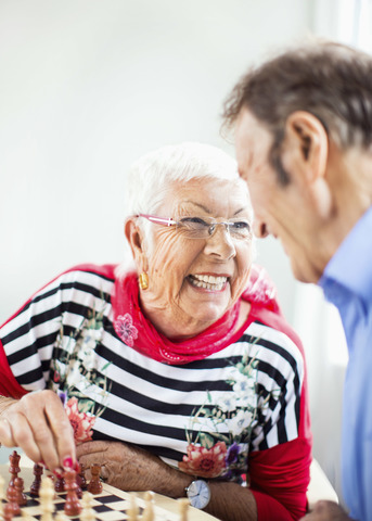 Happy senior couple looking at each other while playing chess in nursing home stock photo