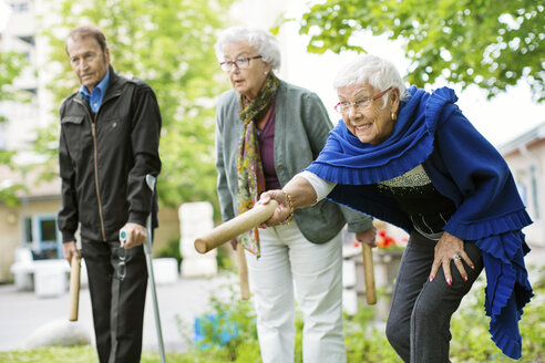 Glückliche ältere Menschen spielen im Park ein Kubb-Spiel - MASF04956