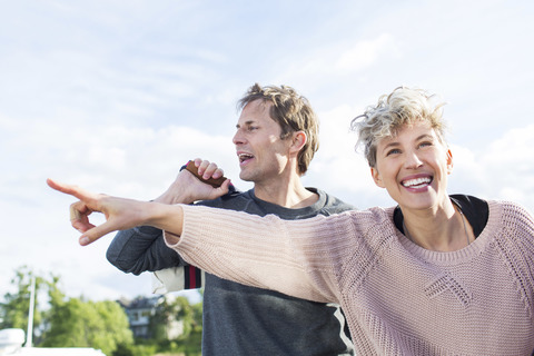 Glückliche Frau zeigt einem Freund etwas gegen den Himmel, lizenzfreies Stockfoto