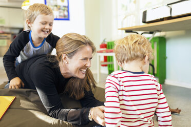 Happy teacher playing with children in kindergarten - MASF04987