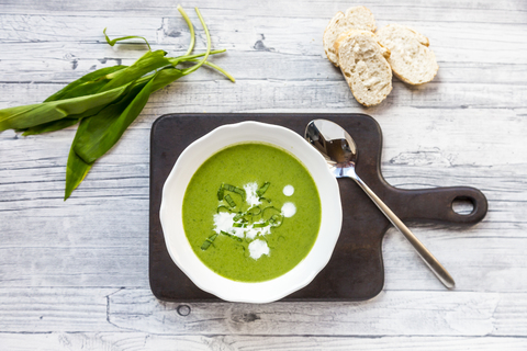 Teller mit Bärlauch-Suppe, garniert mit Bärlauch und Sahne, lizenzfreies Stockfoto