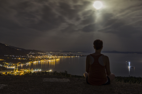 Griechenland, Pagasetischer Golf, Frau genießt Blick auf Volos bei Nacht, Vollmond, lizenzfreies Stockfoto