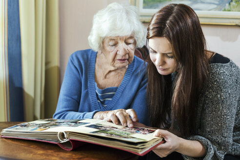 Großmutter und Enkelin betrachten ein Fotoalbum im Haus - MASF05030