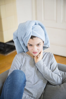 Porträt eines Mädchens mit Handtuch-Turban, das zu Hause auf der Couch sitzt - LVF06883
