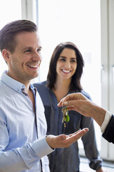 Cropped image of real estate agent handing over keys to couple in new house - MASF05043