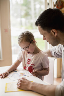 Vater hilft einem behinderten Mädchen beim Lernen zu Hause - MASF05050