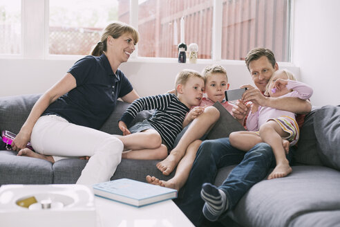 Familie benutzt Smartphone auf dem Sofa zu Hause - MASF05058