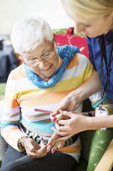 Female caretaker filing senior woman's fingernails at nursing home - MASF05066