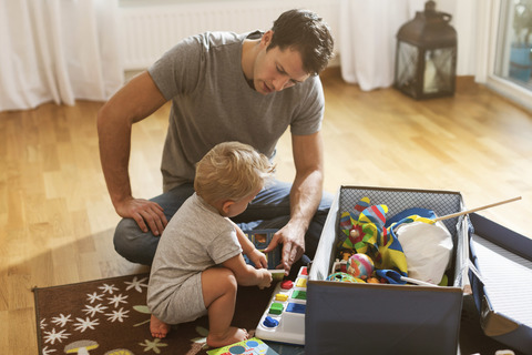 Vater und kleiner Junge spielen Spielzeug auf dem Boden zu Hause, lizenzfreies Stockfoto