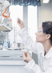 Wissenschaftlerin gießt im Labor eine Chemikalie in ein Becherglas - MASF05086