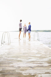In Handtücher gewickelte Freunde stehen am Rande der Strandpromenade gegen den klaren Himmel - MASF05098