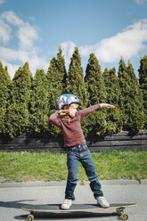 Full length of boy posing while standing on skateboard at yard - MASF05123