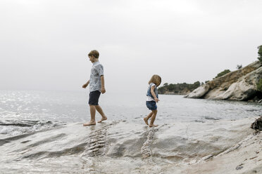 Griechenland, Chalkidiki, Bruder und kleine Schwester spielen zusammen am Strand - KMKF00158