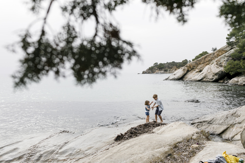 Greece, Chalkidiki, brother and little sister playing together on the beach stock photo