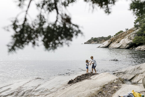 Griechenland, Chalkidiki, Bruder und kleine Schwester spielen zusammen am Strand - KMKF00163