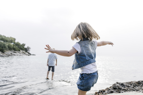 Griechenland, Chalkidiki, Rückenansicht eines kleinen Mädchens beim Spielen am Strand, lizenzfreies Stockfoto