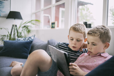 Brüder benutzen digitales Tablet auf dem Sofa zu Hause - MASF05130