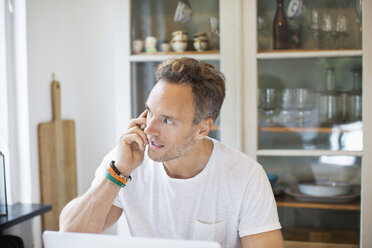 Geschäftsmann, der zu Hause mit seinem Handy telefoniert - MASF05149