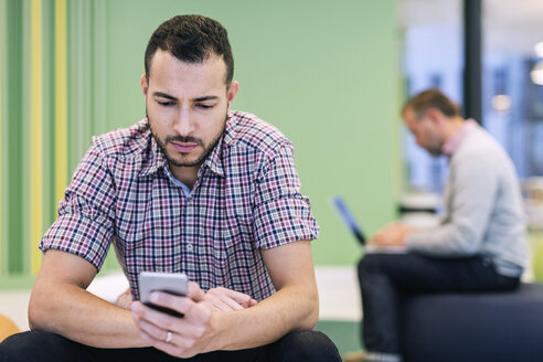 Businessmen using technologies at lobby in modern office - MASF05156