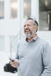 Businessman laughing while communicating through headphones in office - MASF05157