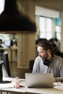 Geschäftsmann mit Computer am Schreibtisch in einem kreativen Büro - MASF05161