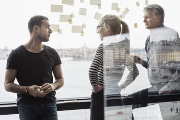 Geschäftskollegen diskutieren am Glasfenster im Büro - MASF05170