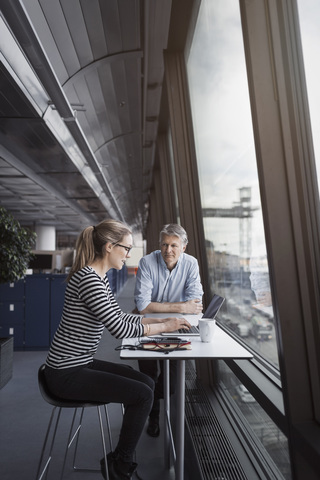 Geschäftsleute sitzen am Tisch am Fenster im Büro, lizenzfreies Stockfoto