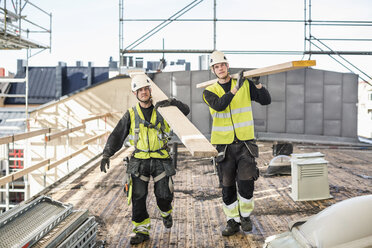 Bauarbeiter tragen Holzbretter auf der Baustelle - MASF05197