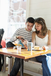 Paar benutzt Mobiltelefone, während es am Restauranttisch sitzt - MASF05198