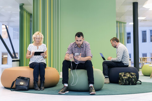 Geschäftsleute nutzen Technologien in einer modernen Büro-Lobby - MASF05210