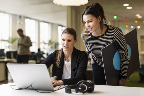 Geschäftsfrauen diskutieren über Laptop im Kreativbüro - MASF05217