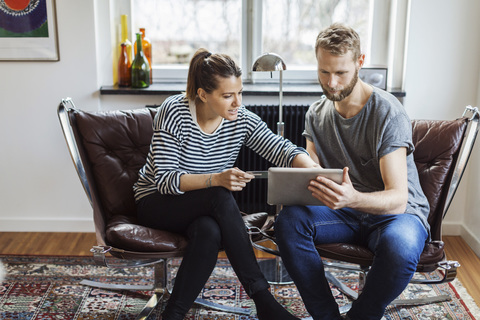 Ein Paar kauft online ein, während es zu Hause auf einem Stuhl sitzt, lizenzfreies Stockfoto