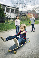 Kinder betrachten Freund Skateboard auf Gehweg vor Haus - MASF05232