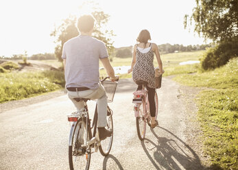 Rückansicht von jungen Freunden, die auf einer Landstraße Fahrrad fahren - MASF05258