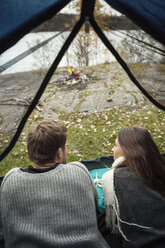 Rückansicht eines jungen Paares im Zelt am Seeufer liegend - MASF05268
