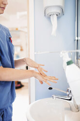 Side view of young nurse washing hands in hospital bathroom - MASF05288