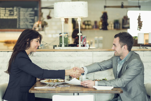 Seitenansicht eines Geschäftsmannes und einer Geschäftsfrau beim Händeschütteln am Restauranttisch - MASF05301