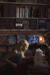 Side view of young female fashion designer using sewing machine in studio - MASF05313