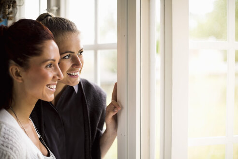 Frauen schauen durch das Fenster eines Sommerhauses hinaus - MASF05323