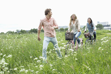 Young friends cycling through field - MASF05333