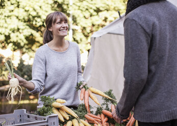 Junge Verkäuferin verkauft Gemüse an einem Marktstand - MASF05335