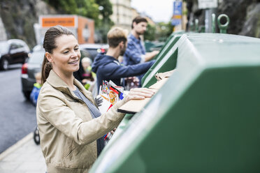 Eine Frau und ihre Freunde werfen wiederverwertbare Materialien in die Recycling-Behälter - MASF05337