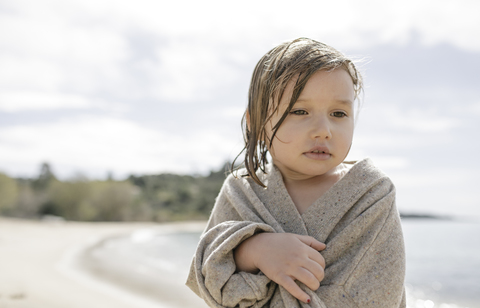Porträt eines traurigen kleinen Mädchens, eingewickelt in eine Strickjacke, lizenzfreies Stockfoto