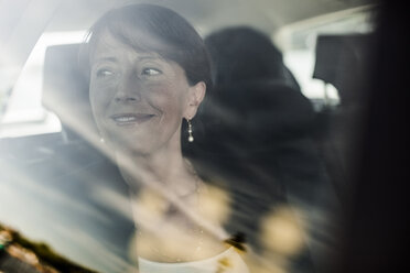 View of businesswoman smiling while looking out through taxi window - MASF05366