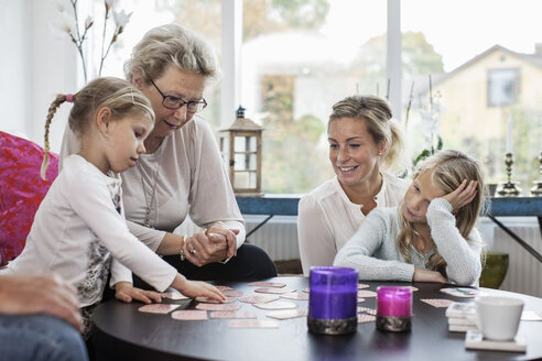 Frauen der dritten Generation spielen zu Hause ein Kartenpuzzlespiel - MASF05384