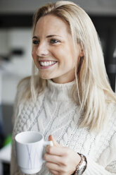 Smiling businesswoman holding coffee mug in office - MASF05393