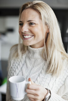 Lächelnde Geschäftsfrau mit Kaffeebecher im Büro - MASF05393
