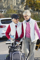 Smiling senior women walking with golf bag outdoors - MASF05409