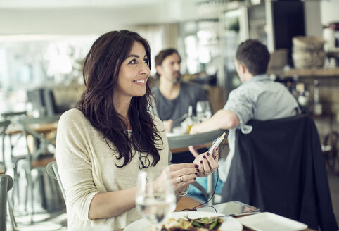 Lächelnde Geschäftsfrau mit Mobiltelefon in einem Restaurant - MASF05420